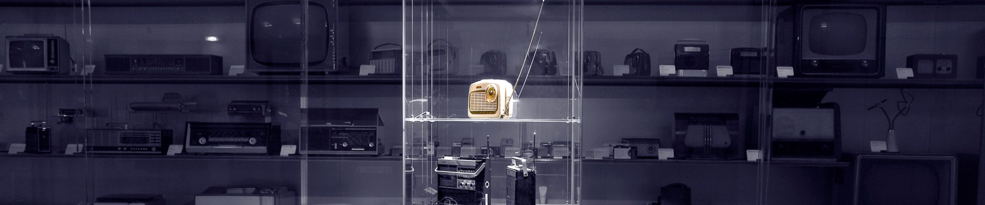 Black and white photo of glass cabinet with object (yellow transistor radio): 